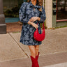 Floral mini dress, with a mix of light and dark blue flower design dress holding red purse with matching red boots or tall boots depending on how tall you are. 