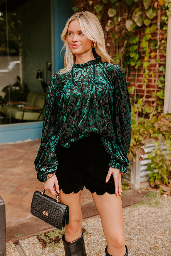 A close-up of a fashionable green velvet top with a bold pattern, paired with scalloped shorts, showcasing a modern take on classic textures and silhouettes.