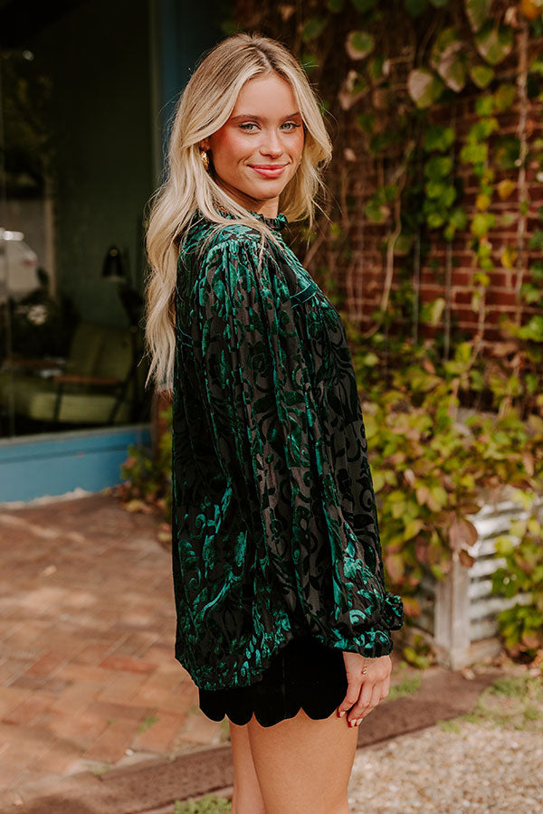 Elegant green velvet top with intricate details and flowing sleeves, paired with black scalloped-edge shorts and knee-high black boots, exuding a chic and timeless style.