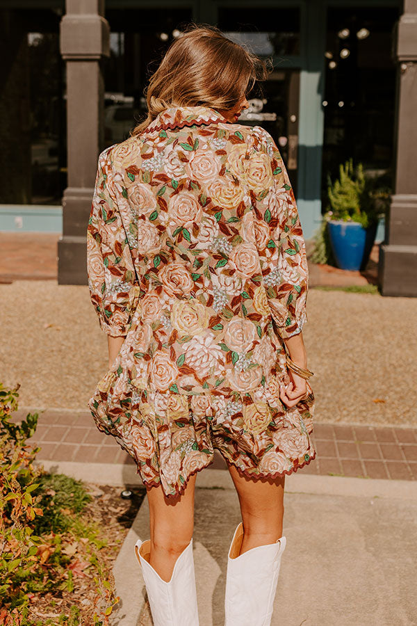 A stunning floral mini dress in shades of green and white, adorned with intricate flower patterns and button details, paired with white boots for a timeless, trendsetting outfit.